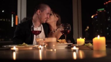 Valentines day dinner for two, kissing couple at the table, romantic date by candlelight, red wine in glasses for family, man and woman relationship anniversary