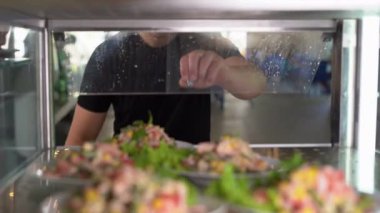 Showcase salad bar with an assortment of food for healthy and dietary meals. Take-out salad. Caucasian man opens the fridge showcase and takes a plate of food. Buffet concept,