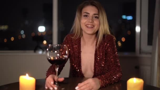 A smiling beautiful girl in an evening dress posing in a modern renovated kitchen. Happy young nice latin woman looking at camera holding a remote video call conversation. — Stok video