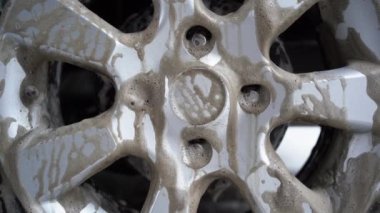Car wash Close-up of tire rims wheels and tires. Modern car wash with high pressure water. Delicate contactless car wash with soap foam. Lots of dirty dripping foam