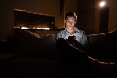 Geceleri cep telefonu olan genç bir adam. Cihazın kullanıcısı bir sosyal ağ oluşturuyor. Gece sohbetinde iletişim. İnternet bağımlılığı. İnsanlar ve teknoloji kavramı