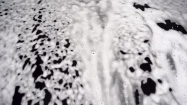 Hand wash with white soap, foam on the body. Car wash with high pressure water.