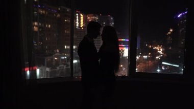 Genç romantik çift geceleri evde birlikte vakit geçirir. Sevgililer pencerenin yanında tutkuyla öpüşürler. Sevgililer Günü 'nde sarılan iki aşık.