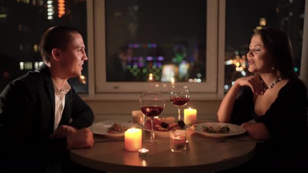 Cena romantica a casa per due. Una coppia amorevole seduta a un tavolo ritratto ravvicinato. concetto per celebrare San Valentino o anniversario. Vino rosso e candele in tavola. — Video Stock