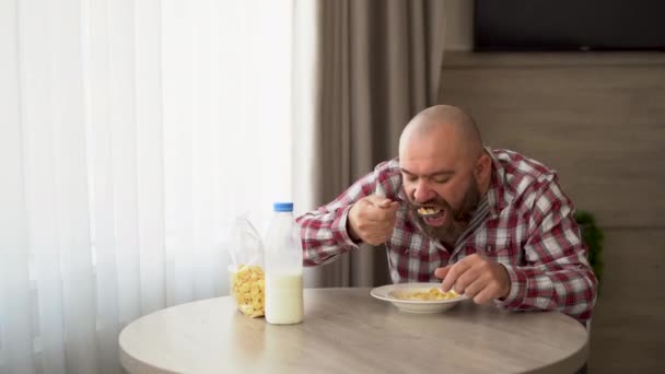 Happy bearded man having breakfast at home in milk and cereal. — Stock Video