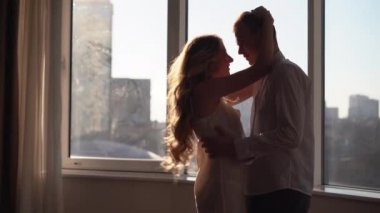 Young couple in love man and woman dancing in the morning at home in the rays of sunlight. Modern apartment with large windows.