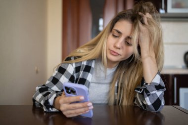 Lonely sad girl is waiting for a phone call, sitting at the table at home. depressed. copy space.