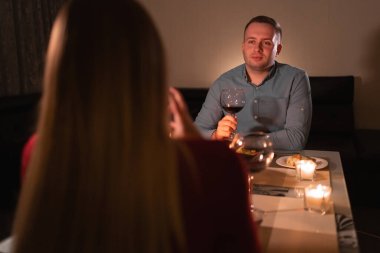 Mutlu genç çift şarap içiyor, romantik randevu, sevgililer gününü kutluyor, erkek ve kadın akşam yemeğinde evde mumlar, sevgililer günü veya doğum günü kutlaması konsepti.