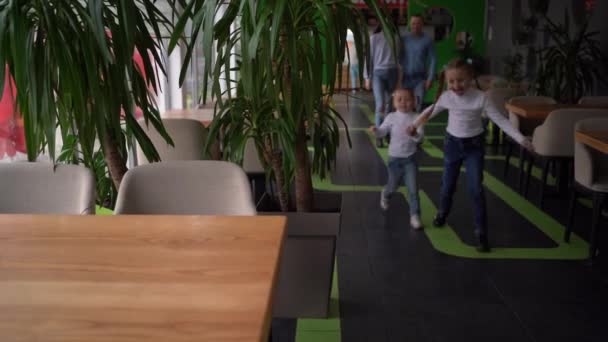 Szczęśliwa rodzina kaukaska spacerująca w kawiarni, dwie dziewczyny biegają do stołu pizzerii, rodzice z córkami spędzają weekend razem w stołówce, szczęśliwe dzieciństwo — Wideo stockowe