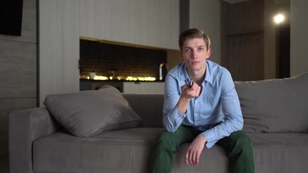 Caucasien jeune homme tente de regarder le jeu à la télévision tandis que sa petite amie le distrait avec des baisers et séduit le ventilateur. 4k - Séquence vidéo