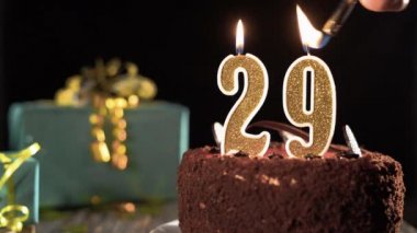 29 numaralı mumlu doğum günü pastası parlak bir şenlik arka planında, çakmağından ateş, 29 yıl boyunca mumları üfle.