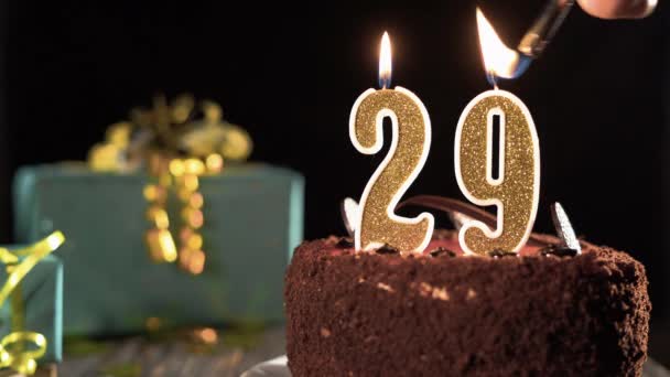 Pastel de cumpleaños con velas número 29 sobre un fondo festivo brillante, fuego de un encendedor, apagar velas durante veintinueve años. — Vídeo de stock