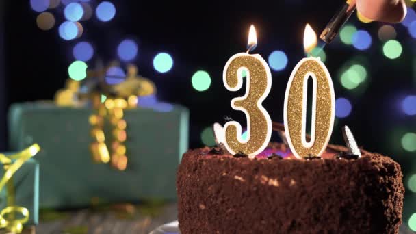 Narozeninový dort se svíčkami číslo 30 na jasném slavnostním pozadí, oheň ze zapalovače, sfouknout svíčky na třicet let. — Stock video