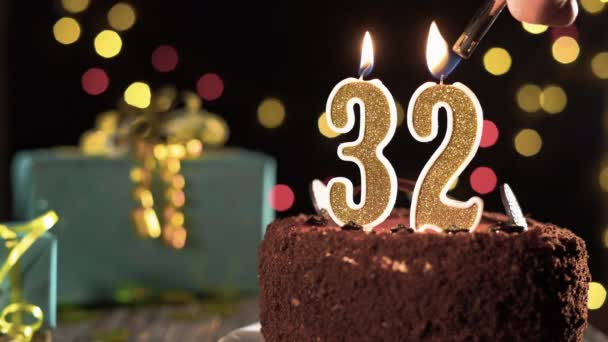 Bolo de aniversário com velas número 32 em um fundo festivo brilhante, fogo de um isqueiro, apague velas durante trinta e dois anos. — Vídeo de Stock