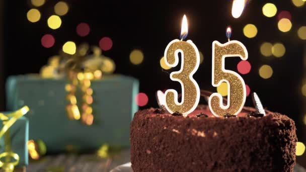 Gâteau d'anniversaire avec bougies numéro 35 sur un fond lumineux de fête, feu d'un briquet, souffler des bougies pendant trente-cinq ans. — Video
