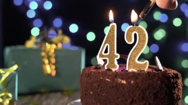 42 numaralı doğum günü mumu masadaki tatlı pastanın üzerinde, 42. doğum günü pastası. Çakmağı yak, bayram mumunu söndür..