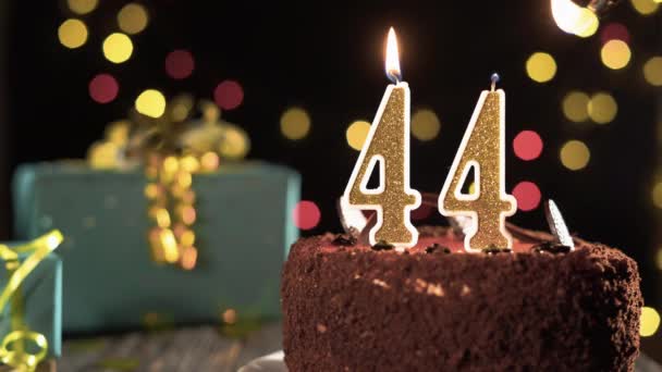 Bougie d'anniversaire numéro 44 sur un gâteau sucré sur la table, 44e anniversaire. Feu du briquet, éteindre la bougie de vacances. — Video