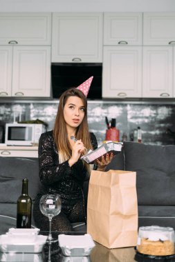 Genç bir kadın doğum günü için restorandan teslimat aldı, tek kullanımlık sofra takımında nefis bir akşam yemeği, hazır yemek, evde doğum günü kutlaması, yaşam tarzı konsepti.