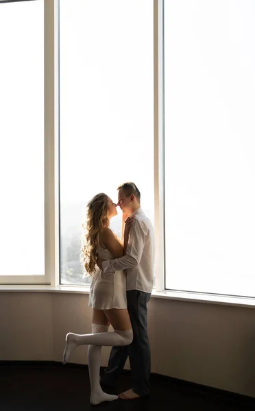 A young couple in love in the morning in casual clothes stands near the window. copy space.