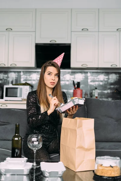 Genç bir kadın doğum günü için restorandan teslimat aldı, tek kullanımlık sofra takımında nefis bir akşam yemeği, hazır yemek, evde doğum günü kutlaması, yaşam tarzı konsepti.