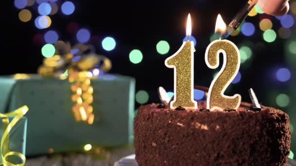 Bougie d'anniversaire numéro 12 sur un gâteau sucré sur la table, 12e anniversaire. Feu du briquet, éteindre la bougie de vacances. — Video