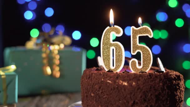 Número sessenta e cinco vela de aniversário em um bolo doce na mesa, 65th aniversário. Fogo do isqueiro, apaga a vela do feriado. — Vídeo de Stock