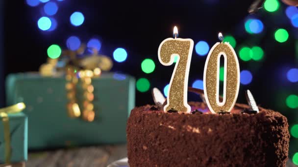 Nummer zeventig verjaardagskaars op zoete taart op tafel, 70ste verjaardag. Vuur van de aansteker, blaas de kerstkaars uit.. — Stockvideo