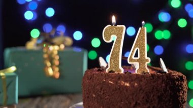 74 numaralı doğum günü mumu masadaki tatlı kekin üzerinde, 74. doğum günü. Çakmağı yak, bayram mumunu söndür..