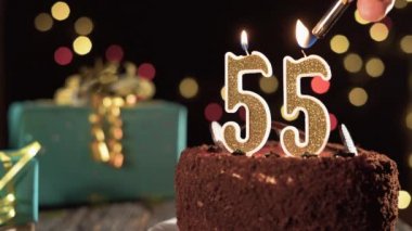 55 numaralı doğum günü mumu masadaki tatlı kekin üzerinde, 55. doğum günü pastası. Çakmağı yak, bayram mumunu söndür..