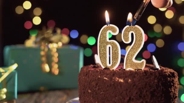 生日蜡烛62号放在桌上的甜蛋糕上，62岁生日。打火机的火，吹灭假日的蜡烛 — 图库视频影像