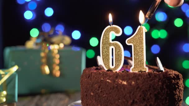 Свеча номер шестьдесят один на сладком торте на столе, на 61-й день рождения. Огонь из зажигалки, задуть праздничную свечу. — стоковое видео