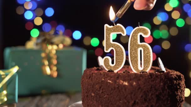 Bougie numéro 56 sur un gâteau sucré sur la table, 56e anniversaire. Feu du briquet, éteindre la bougie de vacances. — Video