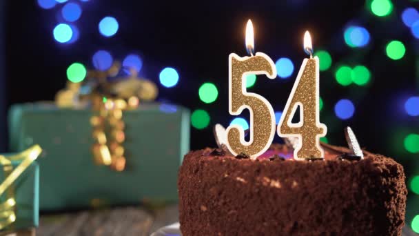 Vela de aniversário número cinquenta e quatro em um bolo doce na mesa, 54th aniversário. Fogo do isqueiro, apaga a vela do feriado. — Vídeo de Stock