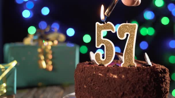 Bougie d'anniversaire numéro 57 sur un gâteau sucré sur la table, 57e anniversaire. Feu du briquet, éteindre la bougie de vacances. — Video