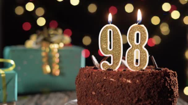 98岁生日蜡烛放在桌上的甜蛋糕上，98岁生日。打火机的火，吹灭假日的蜡烛. — 图库视频影像