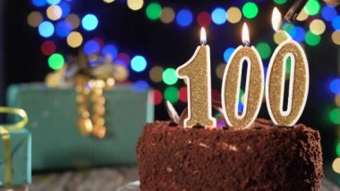 100 numaralı doğum günü mumu masadaki tatlı kekin üzerinde, 100. doğum günü. Çakmağı yak, bayram mumunu söndür..