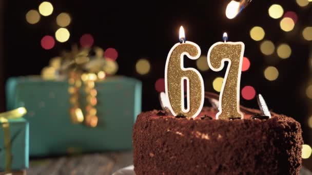 Číslo šedesát sedm narozeninové svíčky na sladkém dortu na stole, 67. narozeniny. Oheň ze zapalovače, sfoukni sváteční svíčku. — Stock video