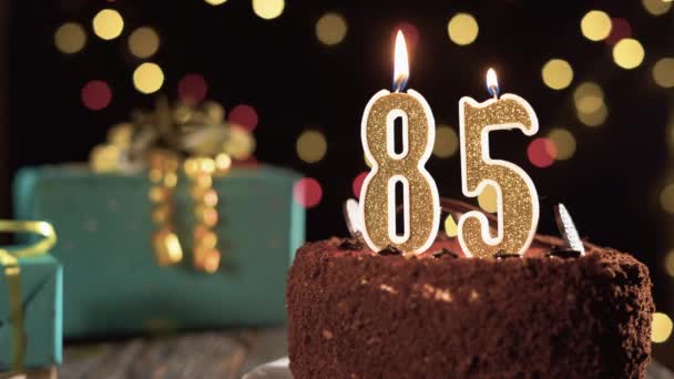 Numer 85 świeczka urodzinowa na słodkim torcie na stole, 85 urodziny. Ogień z zapalniczki, zdmuchnij świąteczną świeczkę. — Wideo stockowe