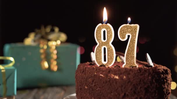 Νούμερο 87 κερί γενεθλίων σε γλυκό κέικ στο τραπέζι, 87α γενέθλια. Φωτιά από τον αναπτήρα, σβήσε το χριστουγεννιάτικο κερί. — Αρχείο Βίντεο
