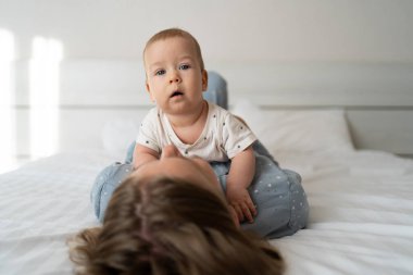 Yatak odasında mutlu bir aile. Genç anne, yeni doğmuş oğlunu karnının üstünde tutarken yatakta yatarken fotokopi odası, mutlu annelik kavramı.
