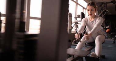 Beyaz kadın spor salonunda kaslarını çalıştırıyor. Sporcu ağırlık kaldırarak spor salonunda antrenman yapar. Boşluğu kopyala.