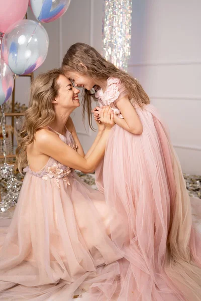 Güzel, uzun elbiseli sevimli anne-kız kucaklaşıyorlar, tatilin tadını çıkarıyorlar, balonlar, sürpriz, hediye, gerçek tatil havası. Doğum günü, yıldönümü ya da yıldönümü tatili