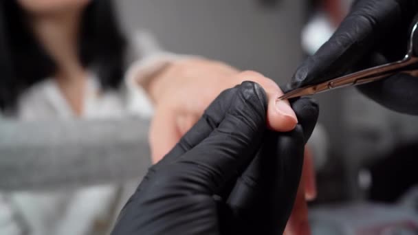 Нанесение маникюра, разрезание кутикулы ножницами. Женщина в маникюре получает маникюр от профессионального косметолога. — стоковое видео