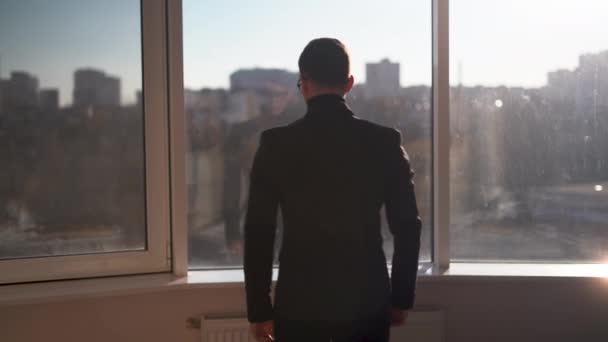Uomo d'affari contemplativo guardando la città attraverso una grande finestra, imprenditore premuroso, uomo d'affari che fa piani, capo considerando — Video Stock