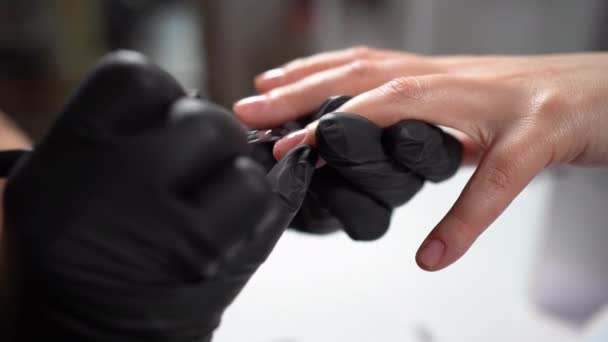 Manicure productieprocessen, macro. Close-up van de klant het aanbrengen van base coat op vrouwelijke nagels met borstel, manicure dragen van zwarte handschoenen, schoonheid — Stockvideo