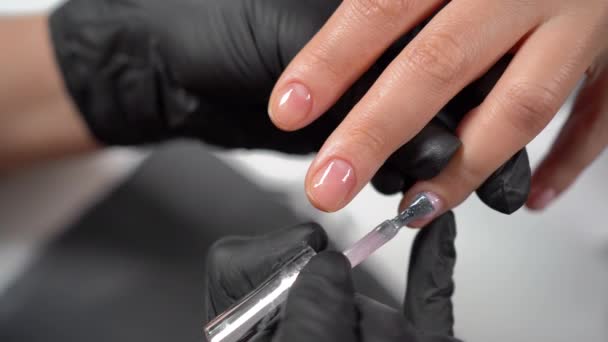 Аппаратный маникюр в салоне красоты, женские руки наносят гель лак, покрывая ногтевую пластину, женские ногти для красоты — стоковое видео