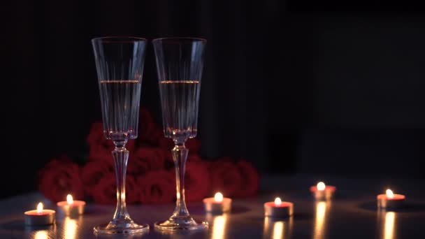 Sparkling champagne in glazen voor een romantische Valentijnsdag, diner bij kaarslicht en een boeket rozen op de achtergrond, 4k — Stockvideo