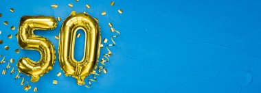50 numaralı altın folyo balonu. 50 yazılı doğum günü ya da yıldönümü kartı. Mavi beton arka plan. Yıldönümü kutlaması. Pankart. Boşluğu kopyala