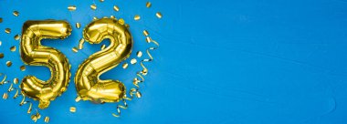 52 numaralı altın folyo balonu. Doğum günü ya da yıldönümü kartı. Üzerinde 52 yazılıydı. Mavi beton arka plan. Yıldönümü kutlaması. Pankart. Boşluğu kopyala