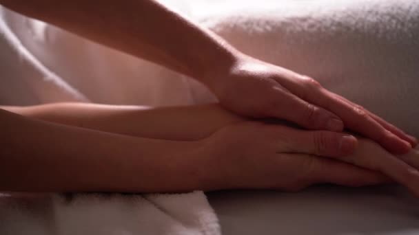 Kvinnlig massageterapeut masserar armar, nyckelben och bröst av en avslappnad klient ligger på en soffa i en skönhetssalong, spa salong närbild av händerna på en kvinnlig massage mästare under arbetet — Stockvideo